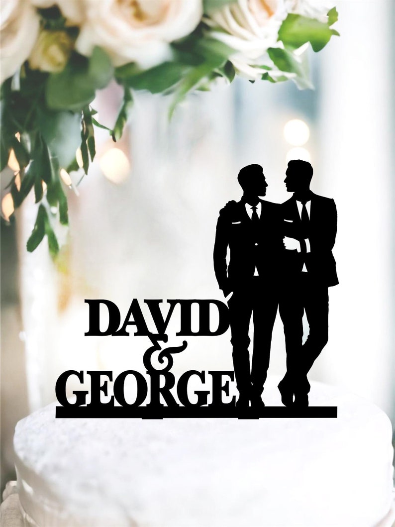 May include: Black silhouette cake topper of two grooms in suits with the text "DAVID & GEORGE" below.