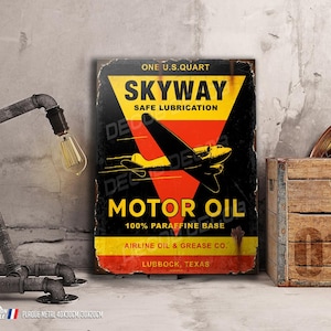 Puede incluir: Un letrero de metal vintage que anuncia Skyway Motor Oil. El letrero presenta un avión amarillo volando sobre un triángulo rojo con texto negro. El texto dice "One U.S. Quart Skyway Safe Lubrication Motor Oil 100% Paraffine Base Airline Oil & Grease Co. Lubbock, Texas."