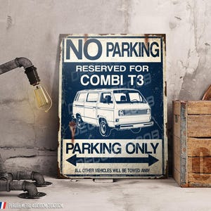 Peut inclure: Une plaque métallique vintage avec le texte "NO PARKING RESERVED FOR COMBI T3" et une illustration de van blanc. La plaque comprend également "PARKING ONLY" et une flèche. La plaque est affichée à côté d'une caisse en bois rustique et d'une lampe en tuyau métallique.