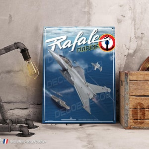 Op de afbeelding: Een vintage-stijl metalen bord met een Rafale Marine gevechtsvliegtuig in de vlucht tegen een blauwe lucht achtergrond. Het bord heeft de tekst "Rafale Marine" en een rode cirkel met een anker erin. Het bord is 40x30cm.