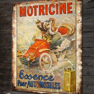 Op de afbeelding: Vintage advertentie voor Motricine Essence voor automobielen. De advertentie toont een stel dat in een rode auto rijdt met een gele blik Motricine op de voorgrond.