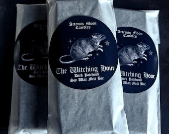 May include: Three wrapped soy wax melt bars. Each bar is sealed in a clear, crinkled paper. A black circular label on each bar reads "Artemis Moon Candles" and "The Witching Hour" with a rat illustration.