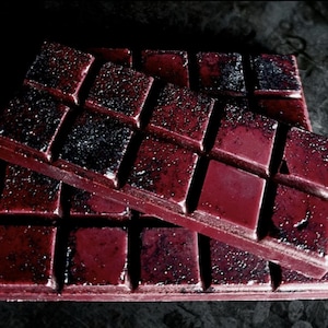 May include: Two stacked bars of dark red chocolate with a glittery, speckled finish. The chocolate is divided into squares.