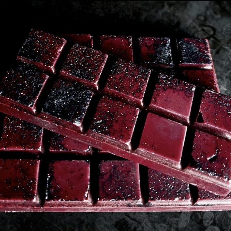 May include: Two stacked bars of dark red chocolate with a glittery, speckled finish. The chocolate is divided into squares.