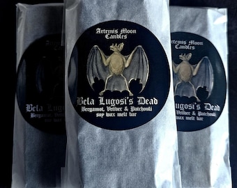May include: Three black and white wax melt bars wrapped in clear plastic. Each bar features a round sticker with a bat illustration and the text "Artemis Moon Candles" and "Bela Lugosi's Dead Bergamot, Vetiver & Patchouli soy wax melt bar".