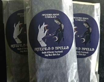 May include: Three white bags with black labels. The labels feature a dark blue circle with a hand and a crescent moon. The text on the label reads "Artemis Moon Candles" and "Rituals & Spells Oudh & Purple Patchouli Soy Wax Melt Bar".