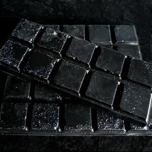 May include: A black silicone mold with a grid of square cavities. The mold is made of flexible silicone and has a smooth, shiny surface.