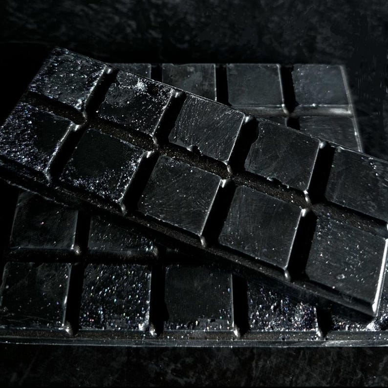 May include: A black silicone mold with a grid of square cavities. The mold is made of flexible silicone and has a smooth, shiny surface.