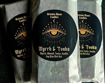 May include: Three wrapped soy wax melt bars. Each bar is packaged in a clear, textured paper. The bars have a black circular label with gold text that reads "Artemis Moon Candles" and "Myrrh & Tonka". The label features an eye design.