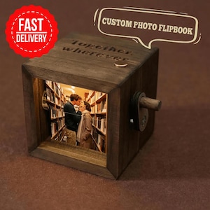 May include: A dark brown wooden custom photo flipbook featuring a photo of a couple kissing. The flipbook has the words "Together, wherever" engraved on top. A red circle with "Fast Delivery" is in the upper left corner.