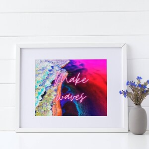 May include: A framed print with a colorful abstract image of a beach and ocean. The text "make waves" is written in pink neon letters.
