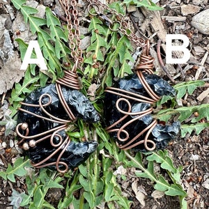 May include: Two black obsidian arrowhead pendants wrapped in copper wire on brown chains. The pendants are labeled A and B.