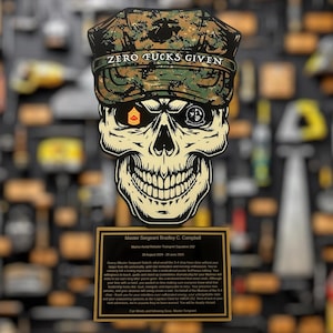 May include: A skull-shaped plaque with a camouflage cap that reads "ZERO FUCKS GIVEN." The skull has military insignia on its eyes. Below is a plaque with text honoring Master Sergeant Bradley C. Campbell.