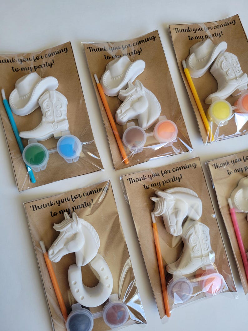 May include: White cowboy-themed paint kits. Each kit includes a cowboy hat, horse head, horseshoe, and cowboy boot, along with paint and a brush. The text "Thank you for coming to my party!" is printed on the packaging.