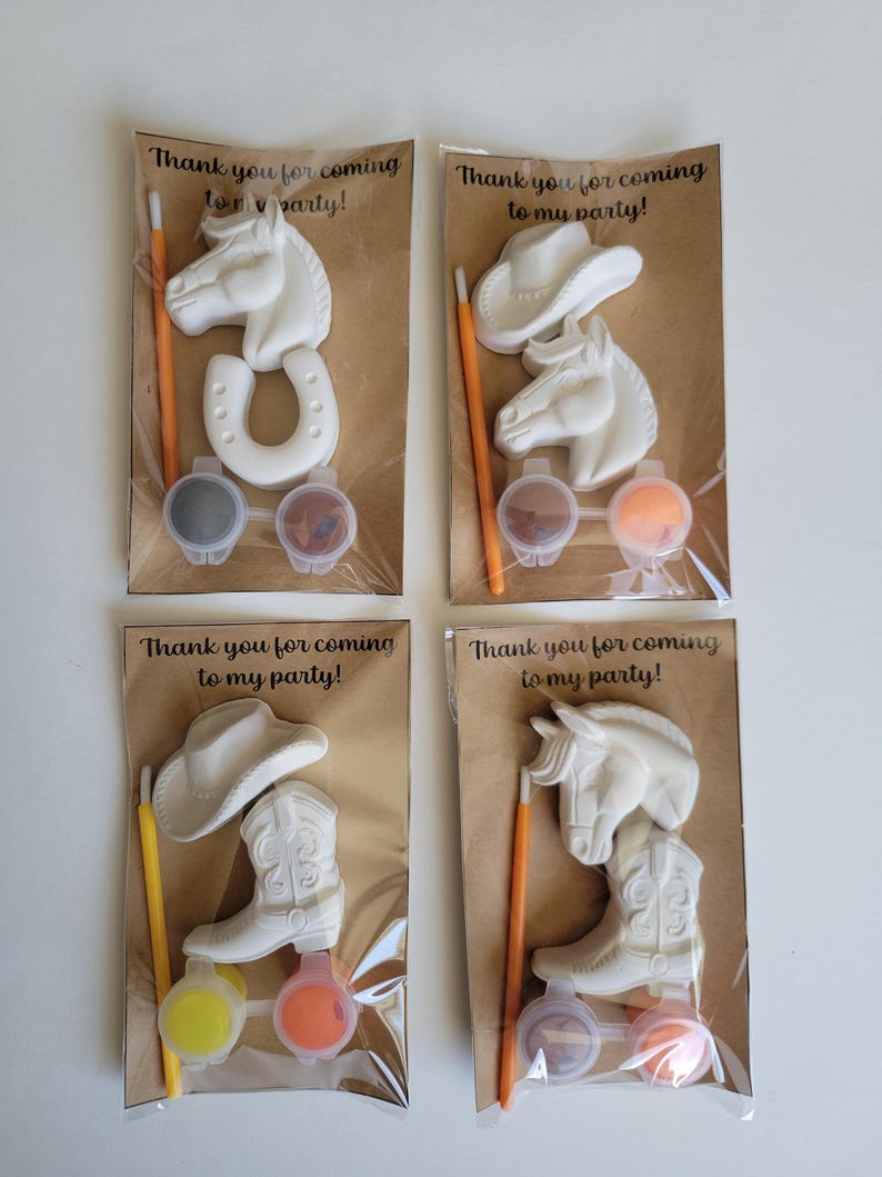 May include: Four party favor sets with a cowboy theme. Each set includes a white horse, horseshoe, cowboy hat, or cowboy boot, paint pots, and a paintbrush. The text "Thank you for coming to my party!" is printed on the packaging.