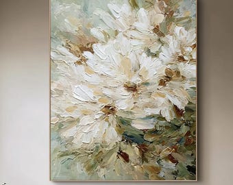 May include: Large floral oil painting with thick brushstrokes in white, cream, and brown hues. The artwork is framed in a gold-colored frame and hangs above a cream-colored tufted sofa with decorative pillows. The room has neutral tones.