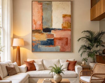 May include: A large rectangular abstract painting featuring thick, textured brushstrokes in shades of peach, cream, navy blue, and ochre, displayed in a thin wooden frame on a light-colored wall above a white sofa.