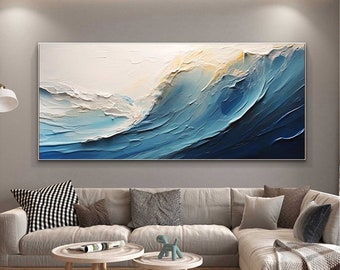 Puede incluir: Pintura abstracta de una ola azul rompiendo contra un fondo blanco. La ola está pintada con trazos gruesos y texturizados de pintura, lo que le da una apariencia tridimensional. La pintura está enmarcada y colgada en una pared de una sala de estar.