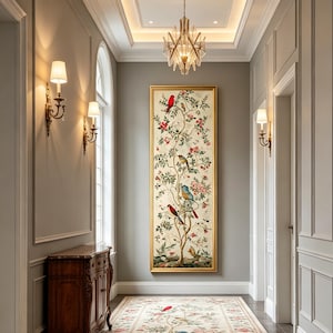 May include: A framed artwork depicting a tree with birds and flowers in a hallway. The artwork is long and rectangular, with a gold frame. The hallway has a patterned rug, wall sconces, and a wooden cabinet.