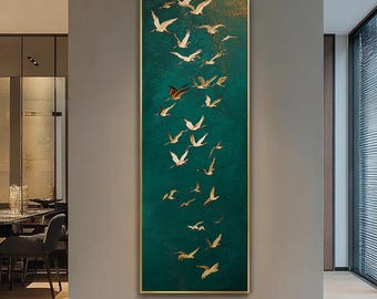 May include: A tall, vertical rectangular wall art piece featuring a deep emerald green background with a flock of white and gold cranes in flight. The birds are depicted in various positions, creating a sense of upward movement and depth.