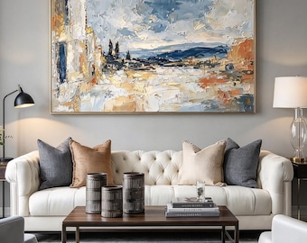 May include: A large rectangular oil painting featuring a textured landscape with shades of blue, white, and orange. The artwork depicts a scene with abstract architectural forms, distant hills, and a cloudy sky, all framed in a thin gold border.