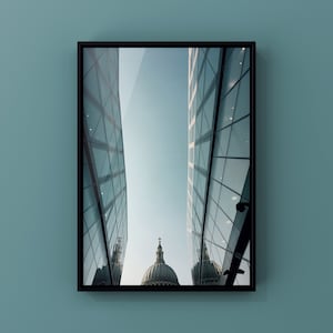 May include: A photograph of a modern building with a glass facade reflecting a large dome-shaped building in the distance. The glass building has a geometric pattern and is partially obscured by the reflection of the dome.