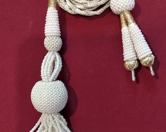 Peut inclure: Tasseau blanc perlé avec une perle ronde et un cordon long et fin. Le pompon est fait de petites perles blanches et a une frange de perles blanches plus grandes.