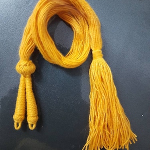 Może przedstawiać: Żółty kaptur do dyplomu z dwoma splecionymi końcami i długim frędzlem.