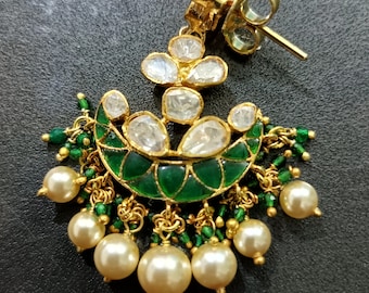 Könnte beinhalten: Ein Paar goldene Ohrringe mit einem grün-weißen Design. Die Ohrringe haben eine Halbmondform mit weißen Steinen und grünem Emaille. Die Unterseite der Ohrringe ist mit einer Fransen aus Perlen und grünen Perlen verziert.
