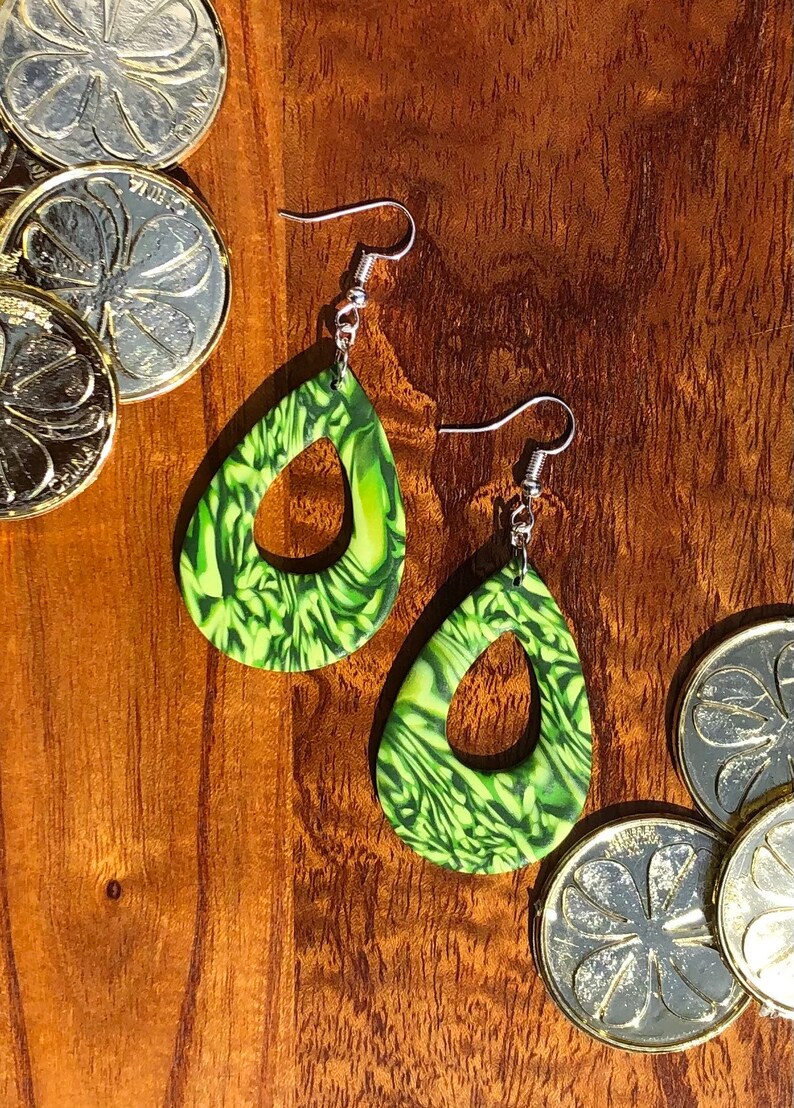 May include: A pair of green and yellow dangle earrings with a swirl pattern. The earrings are made of polymer clay and have a silver hook.