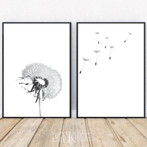 May include: A set of two black and white minimalist art prints featuring a dandelion with seeds blowing in the wind. The first print shows a single dandelion with seeds blowing away. The second print shows multiple dandelion seeds blowing in the wind.