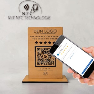 Op de afbeelding: Een houten displaystandaard met een QR-code en de tekst "DEIN LOGO". Een smartphone toont een beoordelingspagina. De standaard heeft de tekst "MIT NFC TECHNOLOGIE" en een afbeelding van een telefoon met een signaal.