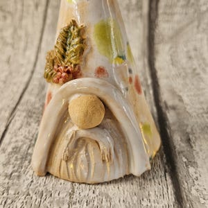 Pu&ograve; includere: Una statuina di gnomo in ceramica con una lunga barba bianca e un naso marrone. Il cappello dello gnomo &egrave; decorato con macchie verdi, gialle e rosse e un piccolo disegno di foglie e bacche. La statuina &egrave; su una superficie di legno.
