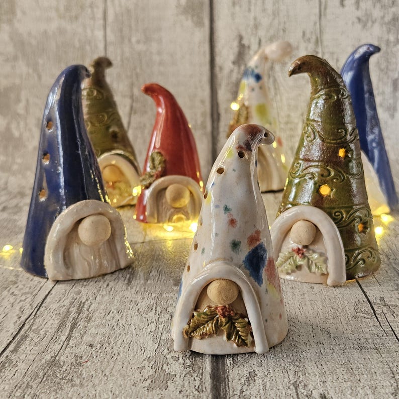 Pu&ograve; includere: Una collezione di statuette di gnomi in ceramica con cappelli alti e a punta in vari colori, tra cui blu, rosso e verde. Ogni gnomo ha un viso rotondo e una piccola apertura ad arco. Alcuni gnomi hanno dettagli decorativi e piccoli fori per la luce.