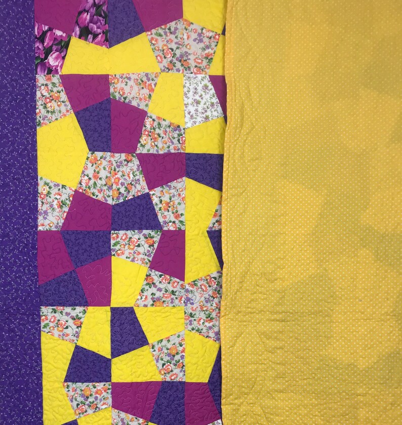 K&ouml;nnte beinhalten: Eine Steppdecke mit Patchwork-Muster aus gelbem, violettem und rosafarbenem Blumenstoff. Die Steppdecke besteht aus geometrischen Formen und ist mit einem einfarbigen gelben Stoff gef&uuml;ttert.