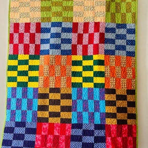 May include: A colourful patchwork quilt featuring a variety of checkered patterns in red, blue, green, yellow, orange, and brown. The quilt is made up of 25 squares, each with a different pattern.