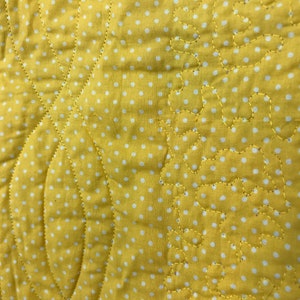 K&ouml;nnte beinhalten: Gelber Stoff mit wei&szlig;en Punkten und einem gesteppten Muster. Das Steppmuster zeigt eine Reihe von geschwungenen Linien und kleinen, abgerundeten Formen.