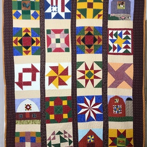 Puede incluir: Un edredón hecho a mano con un diseño de patchwork con varios bloques geométricos y temáticos de granja. El edredón presenta un borde marrón y una variedad de colores, incluyendo rojo, azul, verde y amarillo. El edredón probablemente está hecho de algodón.
