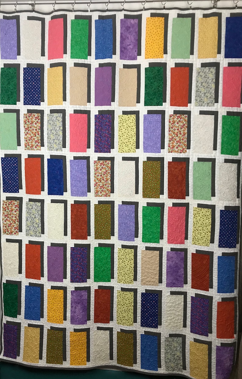 May include: A quilt with a patchwork design featuring a variety of colors and patterns. The quilt is made up of squares and rectangles, each with a different fabric. The colors include red, blue, green, yellow, purple, and white. The patterns include floral prints, polka dots, and geometric designs.