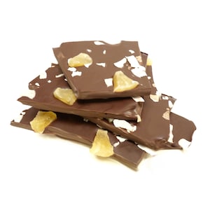 May include: Dark chocolate bark with pieces of candied ginger and coconut flakes. The chocolate is broken into irregular pieces and stacked on a white background. The ginger is a light yellow color.
