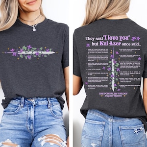 May include: Dark gray t-shirt featuring a sword design with purple flowers and text. The front of the shirt displays the sword, while the back has text that reads "They said 'I love you' but Kai Azer once said..." and a list of quotes.