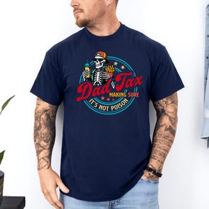 Pode incluir: Camiseta azul marinho com um gr&aacute;fico que diz "Dad Tax" em escrita vermelha, apresentando um esqueleto segurando uma bebida e batatas fritas. O design inclui o texto "Making Sure It's Not Poison" em um padr&atilde;o circular.