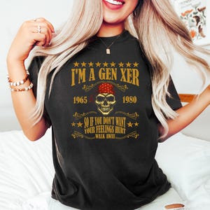 Op de afbeelding: Zwart T-shirt met een vintage-stijl grafische afbeelding met de tekst "I'm a Gen Xer 1965 - 1980" met een schedel met een rode bandana. De afbeelding zegt ook "So if you don't want your feelings hurt walk away."