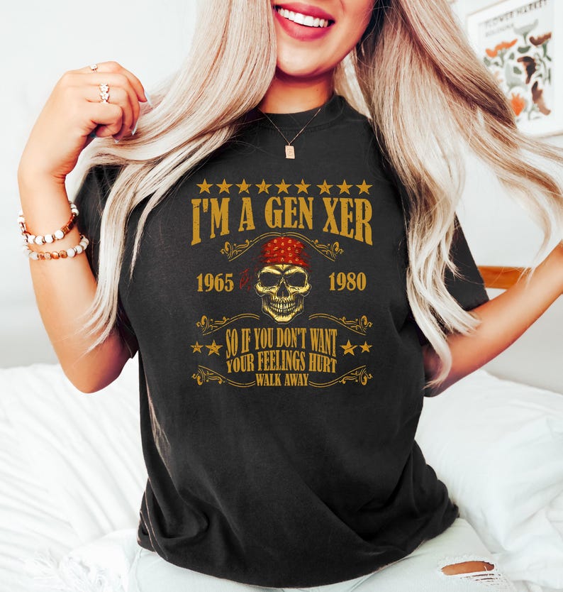 Op de afbeelding: Zwart T-shirt met een vintage-stijl grafische afbeelding met de tekst "I'm a Gen Xer 1965 - 1980" met een schedel met een rode bandana. De afbeelding zegt ook "So if you don't want your feelings hurt walk away."