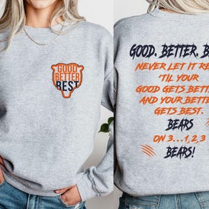 May include: A grey sweatshirt with the words "GOOD BETTER BEST" in a bear-shaped design on the front. The back of the sweatshirt features the phrases "GOOD. BETTER. BEST. NEVER LET IT REST" and "BEARS ON 3...1,2,3 BEARS!"