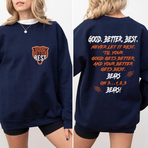 May include: Navy blue sweatshirt featuring the text "GOOD BETTER BEST" and a bear logo on the front. The back of the sweatshirt has the text "GOOD. BETTER. BEST. NEVER LET IT REST. 'TIL YOUR GOOD GETS BETTER, AND YOUR BETTER GETS BEST. BEARS ON 3...1,2,3 BEARS!"