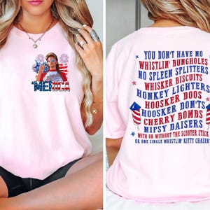 Pode incluir: T-shirt rosa claro com um gr&aacute;fico na frente com uma pessoa usando &oacute;culos de sol e uma bandeira, com a palavra "MERICA". A parte de tr&aacute;s da camisa tem uma lista de frases humor&iacute;sticas.