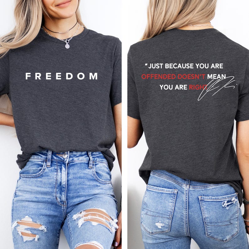 May include: Dark gray t-shirt with the word "FREEDOM" printed in white on the front. The back of the shirt features the quote "JUST BECAUSE YOU ARE OFFENDED DOESN'T MEAN YOU ARE RIGHT" in white and red.