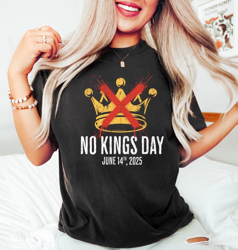May include: Black t-shirt with a gold crown design crossed out in red, and the text "NO KINGS DAY JUNE 14TH, 2025". The shirt is a dark color and has a vintage look.