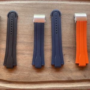 Peut inclure: Six bracelets de montre de différentes couleurs, dont noir, bleu marine et orange. Chaque bracelet a un fermoir en métal et des trous de réglage. Les bracelets sont en matériau souple, conçus pour une montre-bracelet.